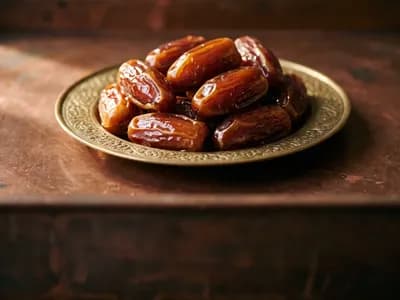 Glossy Medjool dates in an embossed brass dish on a dark copper surface