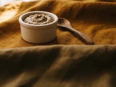Wholegrain Dijon mustard in a white porcelain crock with a wooden spoon